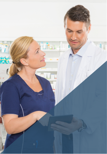 Female nurse in blue scrubs talks with male pharmacist in lab coat
